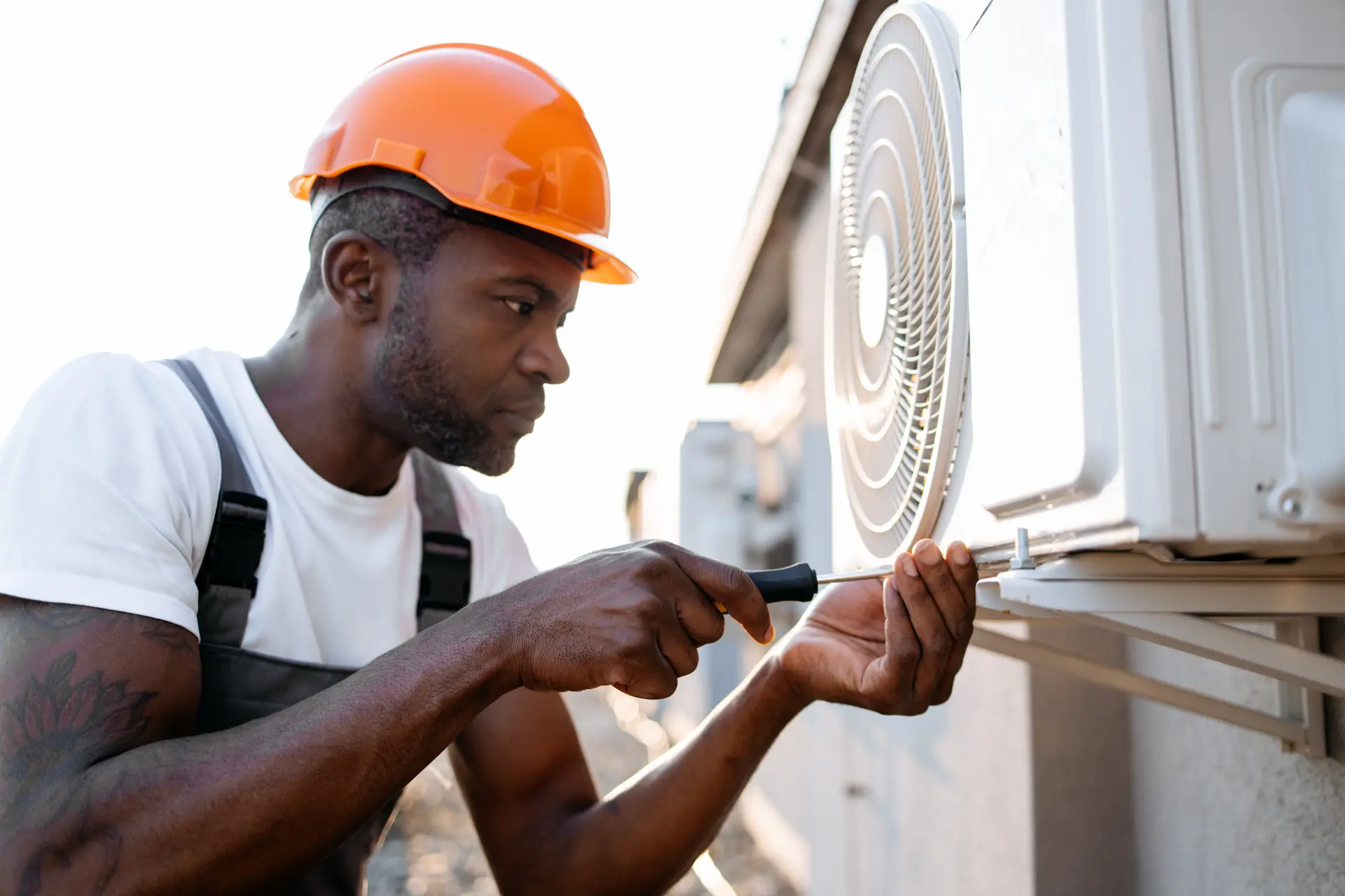 Craftsman repairing an air conditioner with a screwdriver